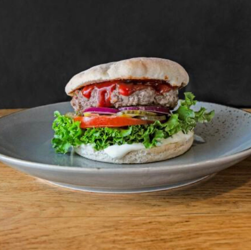Ein Classic Burger mit Rinderpatty, Salat, Tomaten, Zwiebeln und Ketchup auf einen Teller, in der Burgerstube Gütersloh